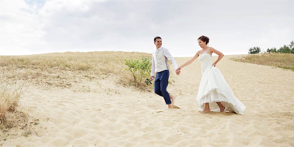 Hochzeitspaar läuft durch den Sand am See in der Nähe von Magdeburg