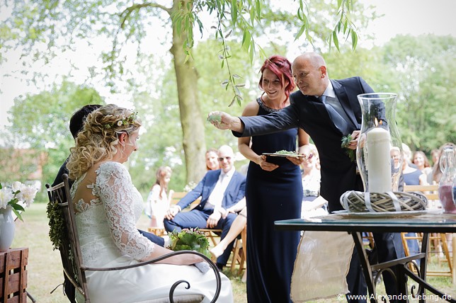 Hochzeitsfotograf Eventschloss Schönfeld - Brautpaar bekommt etwas von Trauzeugen überreicht