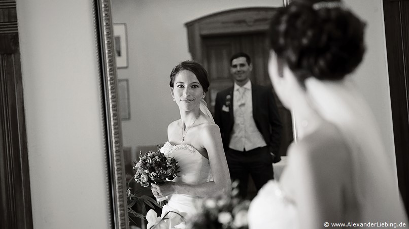 Hochzeitsfotograf Standesamt Barleben / Robinien-Hof Gommern - Braut lächeln über den Spiegel vor Ihr Ihren Bräutigam an