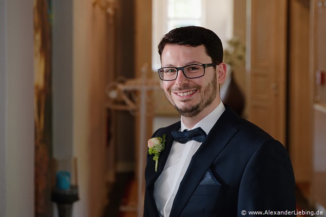 Hochzeitsfotograf Eventschloss Schönfeld - Bräutigam wartet lächelnd auf seine Braut