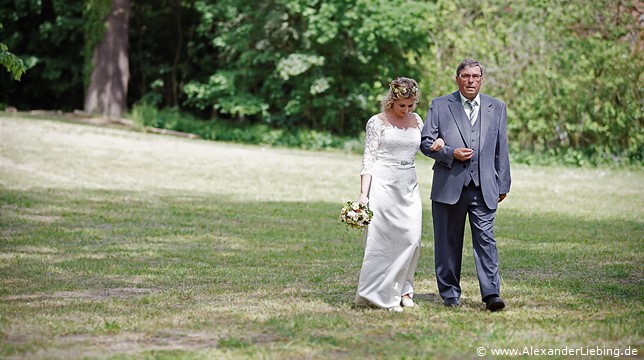 Hochzeitsfotograf Eventschloss Schönfeld - Brautvater führt Tochter über den Rasen