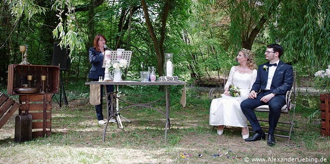 Hochzeit - Hochzeit, freie Trauung Hochzeitsfotograf Eventschloss Schönfeld - Standesbeamtin liest etwas vor, Brautpar hört zu