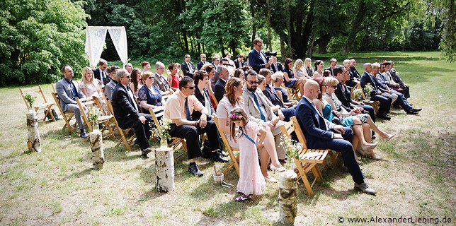 Hochzeit - Hochzeit, freie Trauung Hochzeitsfotograf Eventschloss Schönfeld - Gäste verfolgen Trauung im Sonnenschein