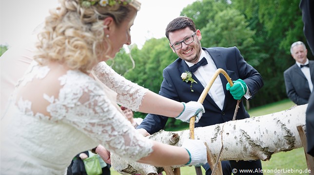 Hochzeit - Begrüßung, Sektempfang und Spielereien Hochzeitsfotograf Eventschloss Schönfeld - Gemeinsames Baumstammsägen