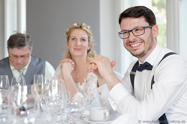 Hochzeit - Hochzeitsfeier Hochzeitsfotograf Eventschloss Schönfeld - Bräutigam sitzt am Tisch