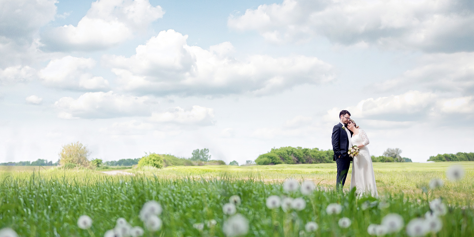 das Brautpaar Sandy und Martin stehen auf einem Feld in der Nähe des Eventschloß Schönfeld