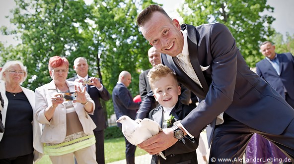 Hochzeit - Begrüßung, Sektempfang und Spielereien Hochzeitsfotograf Standesamt Magdeburg / Gartenhaus im Stadtpark - Papa und Sohn halten Taube in der Hand