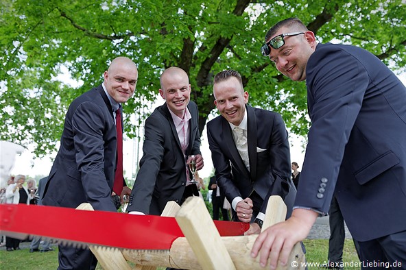 Hochzeit - Begrüßung, Sektempfang und Spielereien Hochzeitsfotograf Standesamt Magdeburg / Gartenhaus im Stadtpark - Trauzeugen helfen beim Baumstammsägen