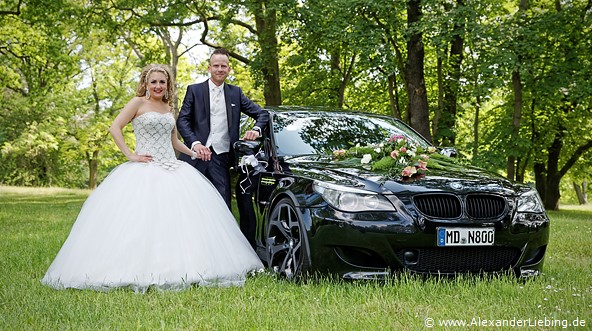 Hochzeit - Brautpaar Hochzeitsfotograf Standesamt Magdeburg / Gartenhaus im Stadtpark - Ehepaar steht neben BMW