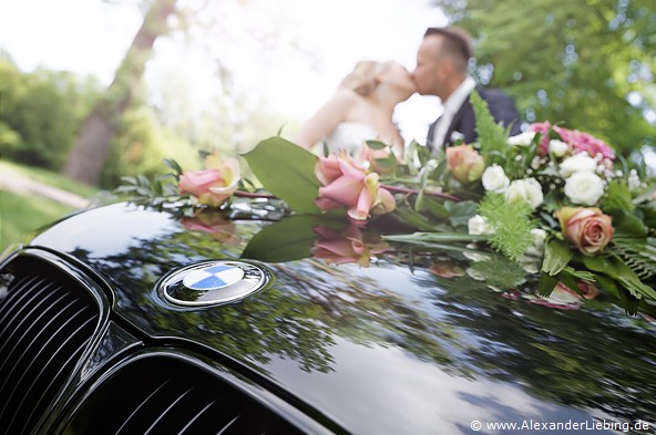 Hochzeitsfotograf Standesamt Magdeburg / Gartenhaus im Stadtpark - Brautpaar küsst sich, im Vordergrund BMW