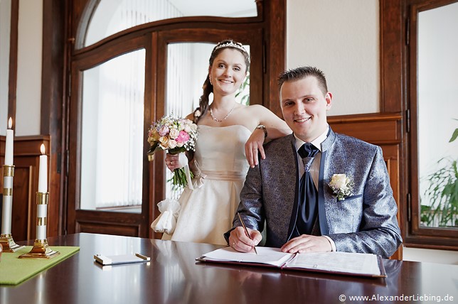 Hochzeitsfotograf Standesamt Magdeburg / Elbelandhaus - ein freches Grinsen beim unterschreiben der Trauurkunde