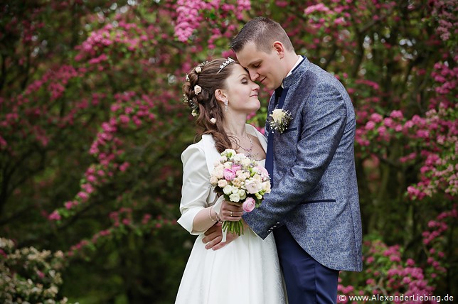 Hochzeit - Brautpaar Hochzeitsfotograf Standesamt Magdeburg / Elbelandhaus - frisch Vermählte stehen vor lila blühendem Busch