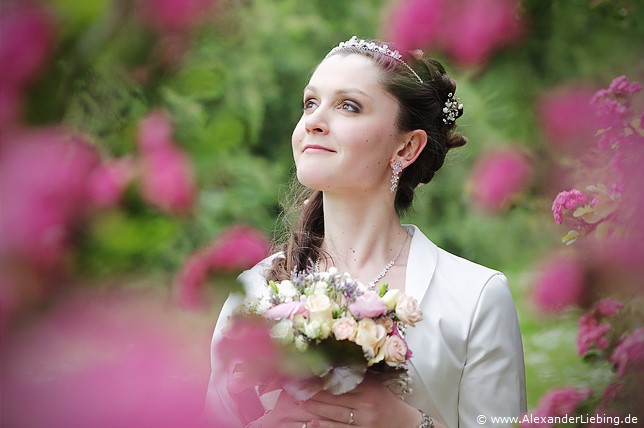Hochzeit - Brautpaar Hochzeitsfotograf Standesamt Magdeburg / Elbelandhaus - Braut steht in Mitten von lila Blüten.
