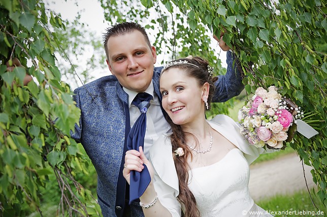 Hochzeitsfotograf Standesamt Magdeburg / Elbelandhaus - Brautpaar guckt durch Äste von Birke.