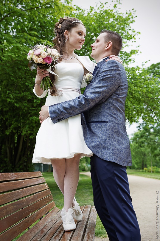 Hochzeit - Brautpaar Hochzeitsfotograf Standesamt Magdeburg / Elbelandhaus - Braut steht auf Bank und schaut Bräutigam an