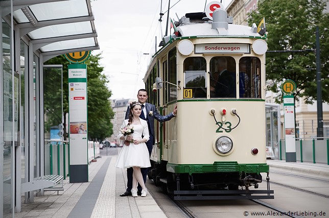 Hochzeitsfotograf Standesamt Magdeburg / Elbelandhaus - Brautpaar lehnt sich an Straßenbahnhaltestelle an historische Straßenbahn