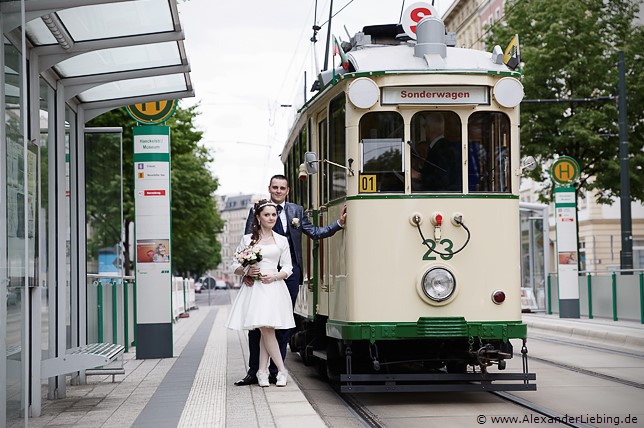 Hochzeit - Brautpaar Hochzeitsfotograf Standesamt Magdeburg / Elbelandhaus - Brautpaar lehnt sich an Straßenbahnhaltestelle an historische Straßenbahn