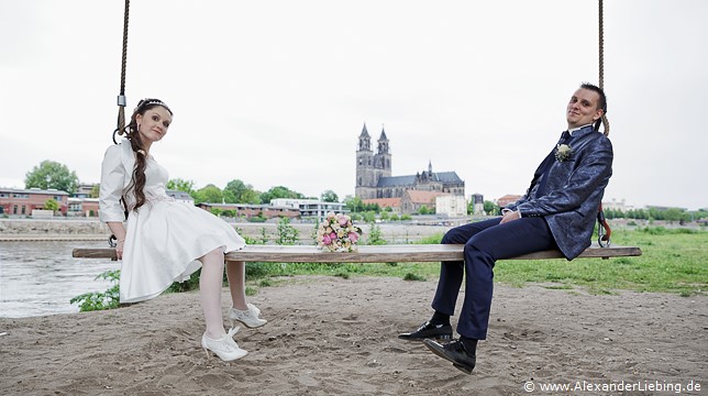 Hochzeit - Brautpaar Hochzeitsfotograf Standesamt Magdeburg / Elbelandhaus - zwischen Braut und Bräutigam liegt Brautstrauß auf Elbschaukel