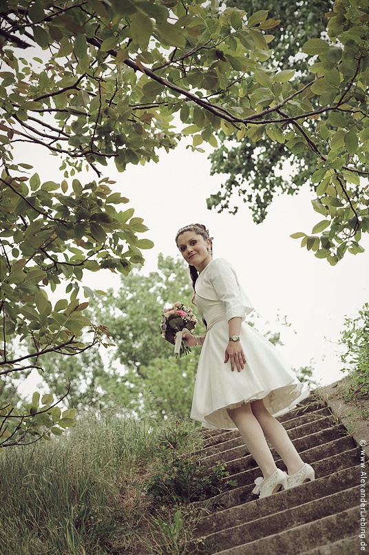 Hochzeit - Brautpaar Hochzeitsfotograf Standesamt Magdeburg / Elbelandhaus - Braut dreht sich auf Treppe zur Elbe um und schaut in Kamera.