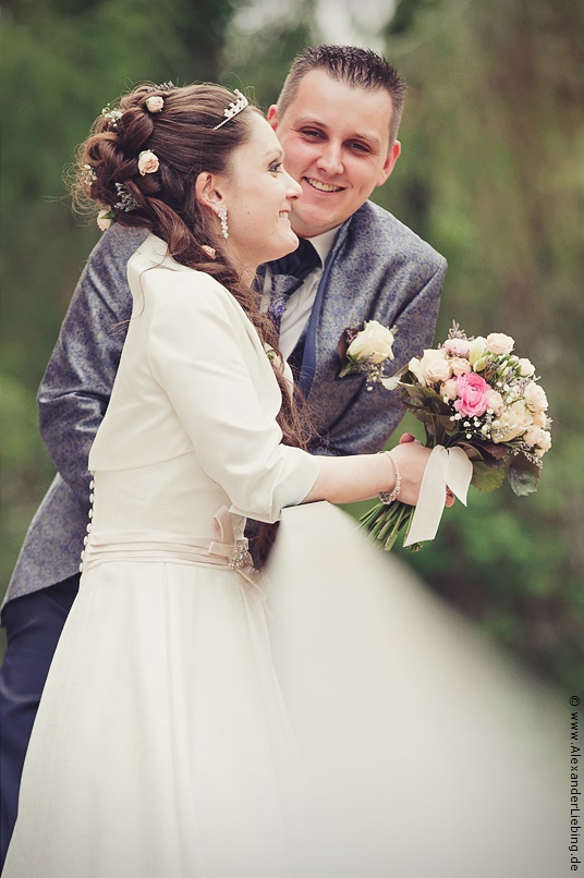 Hochzeit - Brautpaar Hochzeitsfotograf Standesamt Magdeburg / Elbelandhaus - Braut hält Brautstrauß, Bräutigam schaut in Kamera