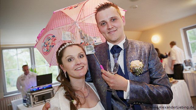 Hochzeitsfotograf Standesamt Magdeburg / Elbelandhaus - Ehepaar hält Regenschirm mit Geldscheinen in der Hand