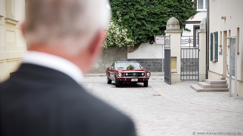 Hochzeit - kurz vor der Trauung Hochzeitsfotograf Standesamt Barleben / Robinien-Hof Gommern - gespannt empfängt der Bratvater seine Tochter, die im roten Ford Mustang vorfährt