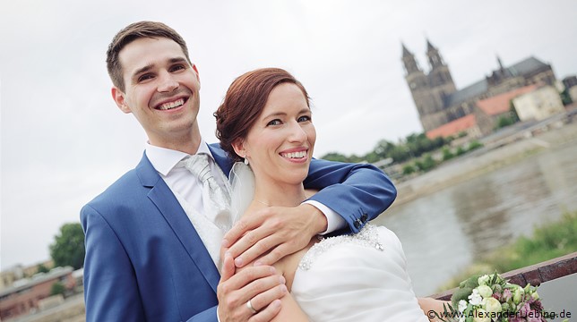 Hochzeit - Brautpaar Hochzeitsfotograf Standesamt Barleben / Robinien-Hof Gommern - Bräutigam hält seine Frau im Arm, Magdeburger Dom im Hintergrund