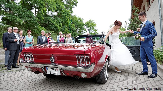 Hochzeit - Hochzeitsfeier Hochzeitsfotograf Standesamt Barleben / Robinien-Hof Gommern - Gentleman pur: der Bräutigam hilft seiner Braut aus dem roten Ford Mustang