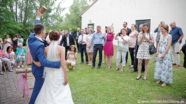 Hochzeit - Hochzeitsfeier Hochzeitsfotograf Standesamt Barleben / Robinien-Hof Gommern - stolz präsentiert der Bräutigam eine Hälfte des Baumstamms