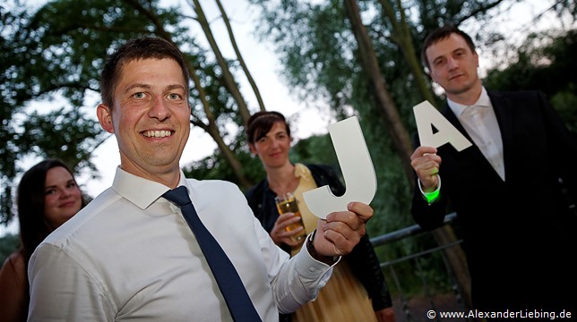 Hochzeit - Hochzeitsfeier Hochzeitsfotograf Standesamt Barleben / Robinien-Hof Gommern - Gäste halten Holz-Buchstaben
