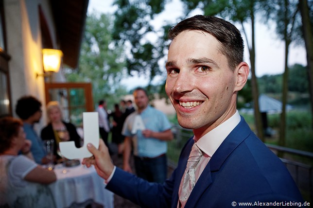 Hochzeitsfotograf Standesamt Barleben / Robinien-Hof Gommern - Bräutigam und Gäste halten Holz-Buchstaben 